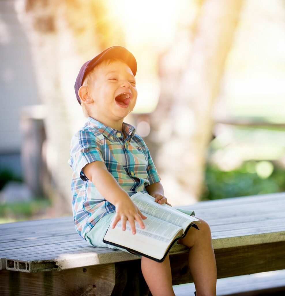 boy sitting on bench while holding a book